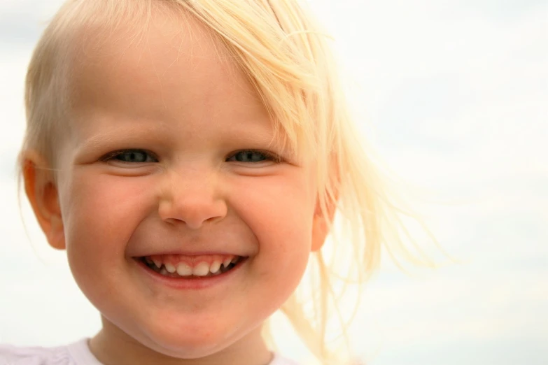 a close up of a child smiling at the camera, a girl with blonde hair, pallid skin, brightly lit, sunlit