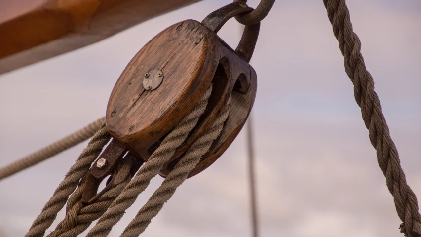 a close up of a pulley on a boat, a portrait, by Robert Brackman, bright sky, medium closeup, wooden, version 3