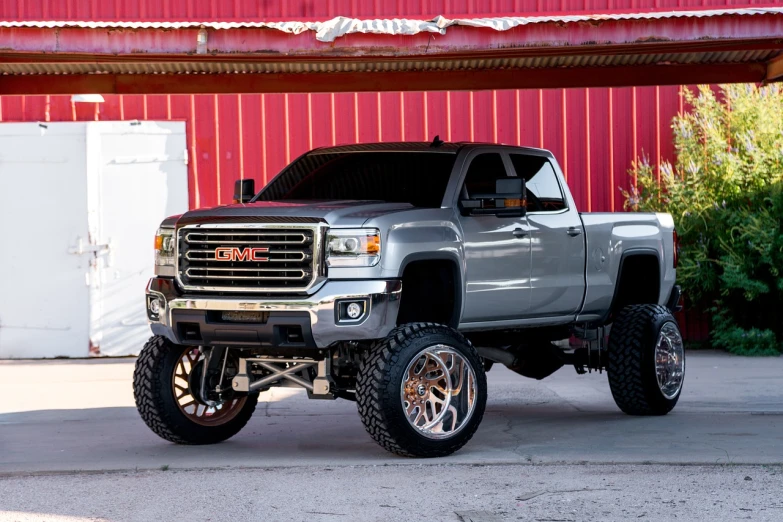 a silver truck parked in front of a red building, inspired by Drew Tucker, featured on instagram, renaissance, detailed alloy wheels, gm, full body shot close up, redneck country