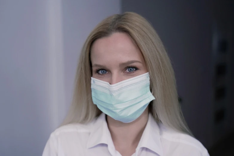 a close up of a person wearing a face mask, by Emma Andijewska, surgical supplies, blonde woman, pastel green, professional picture