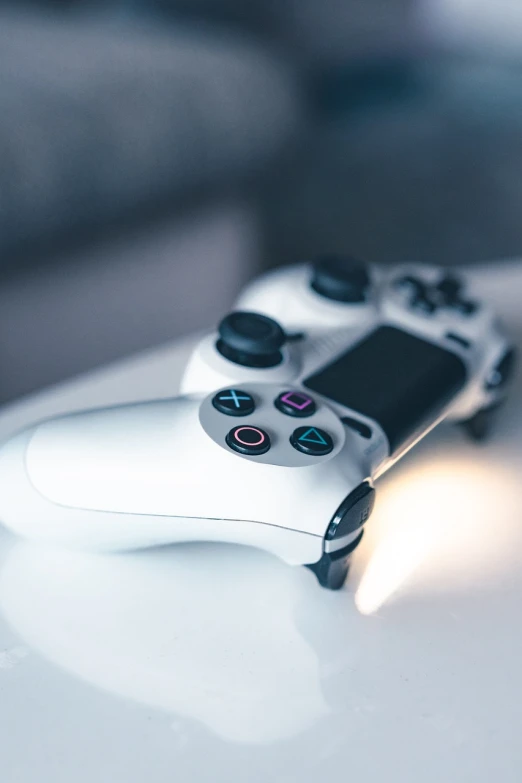 a video game controller sitting on top of a table, a picture, by Matija Jama, glossy white, playstation 4, crisp and sharp, brightly lit