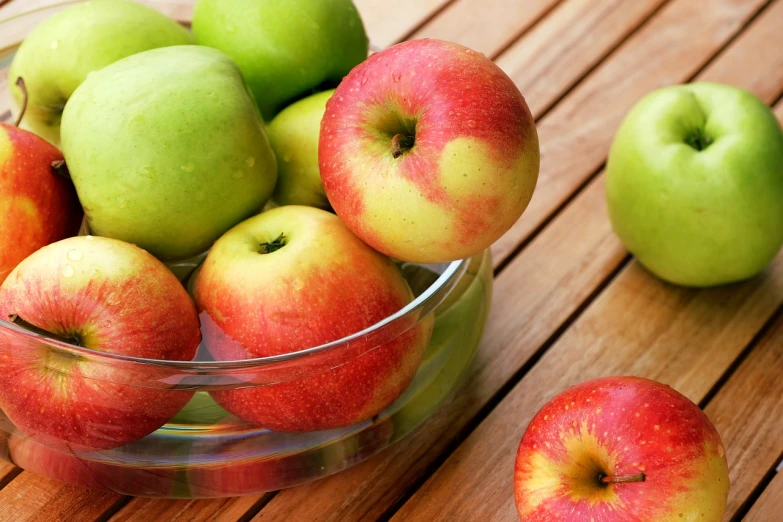 a bowl of apples sitting on top of a wooden table, pexels, vibrant red and green colours, istockphoto, plates of fruit, semi-transparent