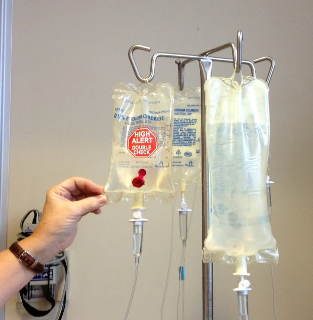 a person holding an ivg in a hospital room, by Jessie Algie, flickr, fluid bag, pouring, artery, cell bars
