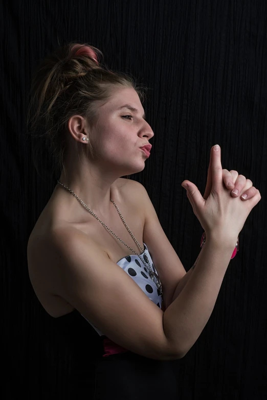 a woman holding a cell phone up to her face, a picture, inspired by Artemisia Gentileschi, figuration libre, posing with crossed arms, dslr photo of a pretty teen girl, black backdrop!, giving the middle finger