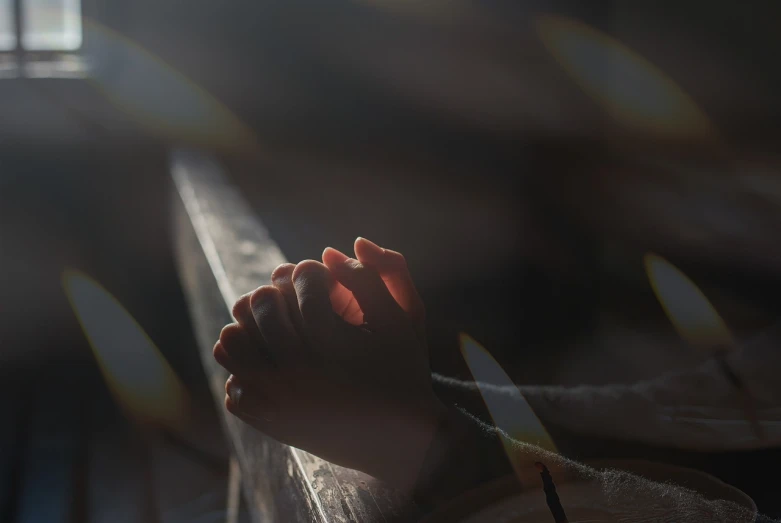 a close up of a person's feet on a bench, a picture, by Andrew Domachowski, happening, praying at the sun, hands crossed, light glare, it is a place of worship