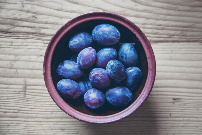 a bowl of plums on a wooden table, a stock photo, dark purple blue tones, high quality product photo, food blog photo, phone photo
