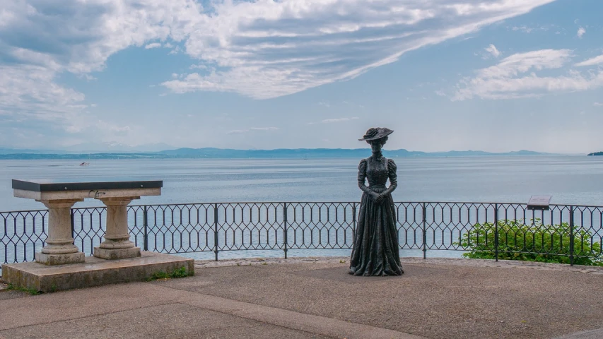 a statue of a woman standing in front of a body of water, a statue, inspired by James Abbott McNeill Whistler, art nouveau, lake baikal in the background, bizzaro, photo taken on a nikon, at the terrace