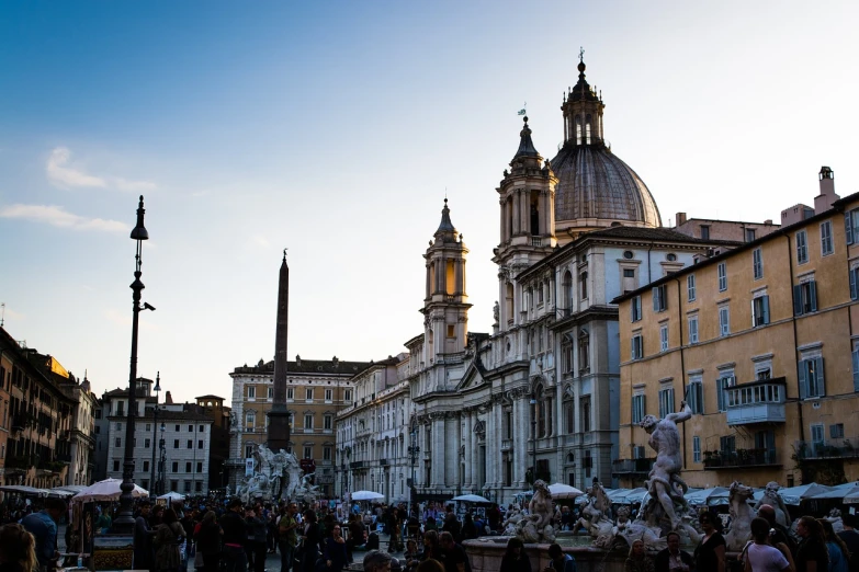 a crowd of people walking down a street next to tall buildings, a photo, by Alessandro Allori, baroque, roman monuments, sun down, marble statues, neoclassical tower with dome