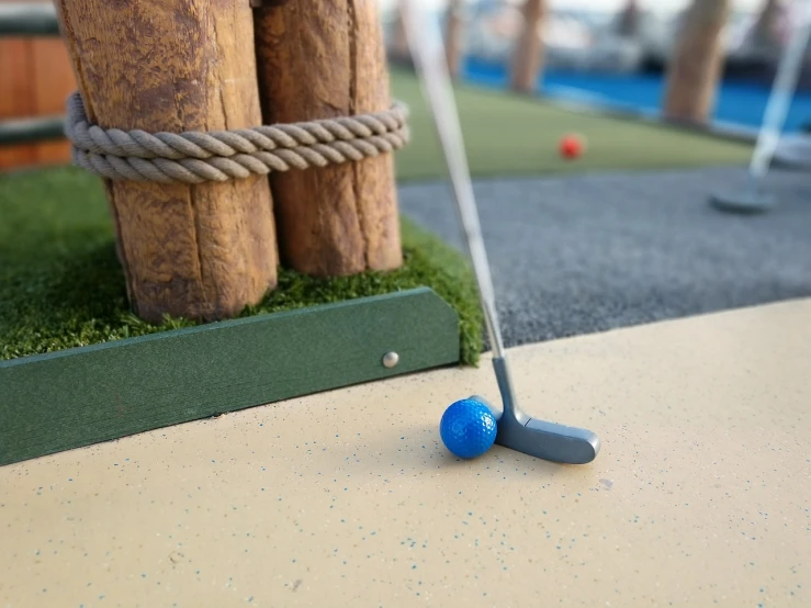 a miniature golf course with a blue ball on the ground, a picture, by Tom Wänerstrand, unsplash, figuration libre, set sail, slight overcast lighting, square, head and shoulder shot