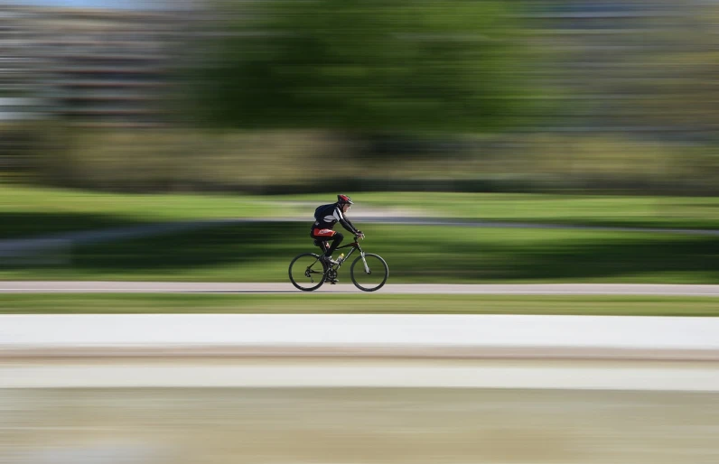 a man riding a bike down a street, a picture, by Michael Sittow, panning shot, in a city park, very accurate photo, high resolution photo