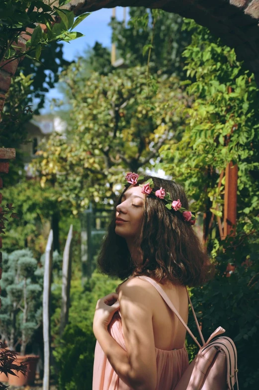 a woman with a backpack and flowers in her hair, a picture, pexels, romanticism, in a garden of a house, pink headband, artem chebokha, connected to nature via vines