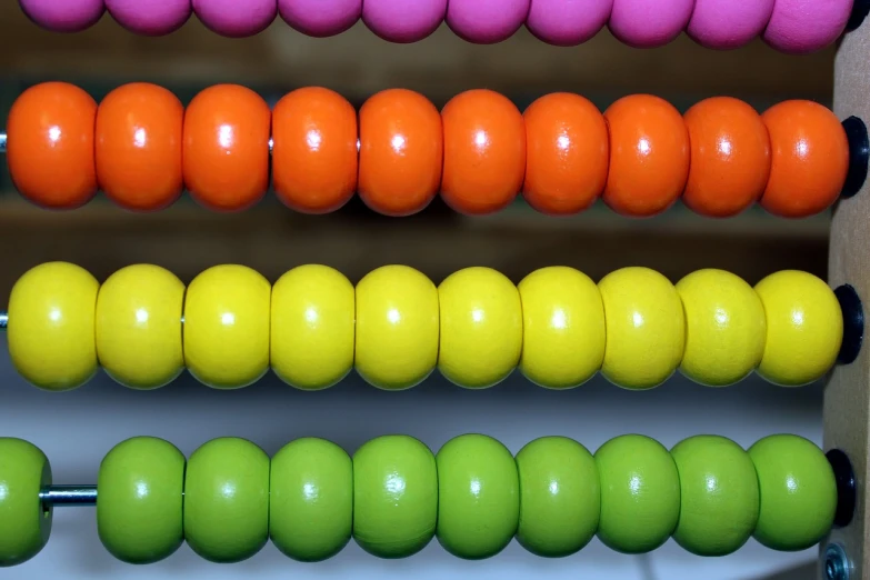 a row of colorful beads sitting on top of a table, a picture, flickr, bauhaus, maths, jamaican colors, fluo details, closeup!!