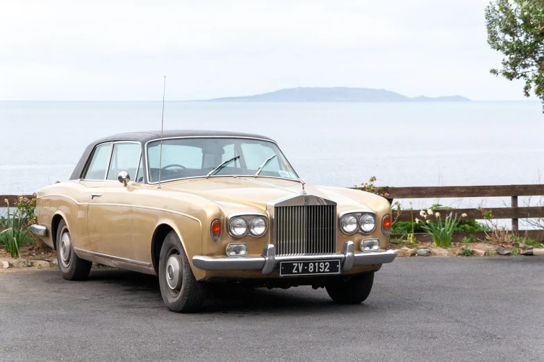 a car parked in a parking lot next to a body of water, renaissance, elegant gold body, new zealand, well preserved, cliffside