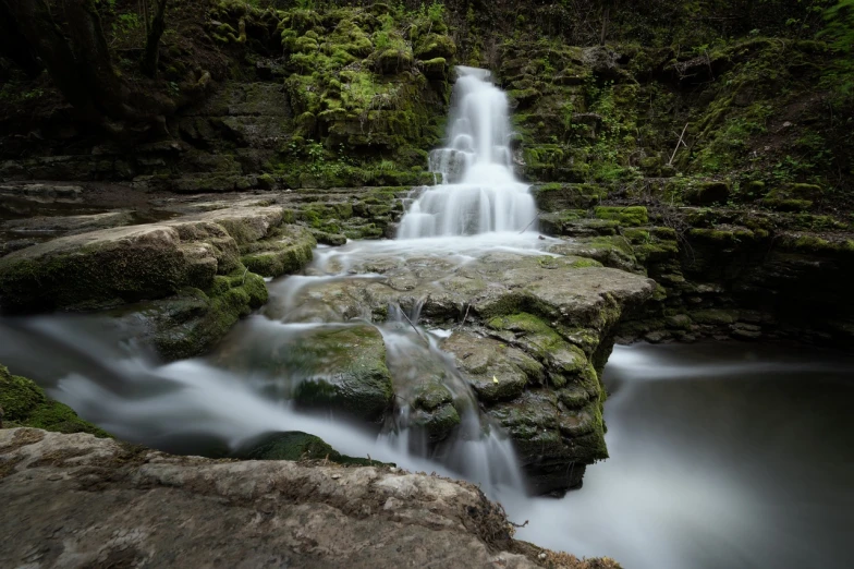 a waterfall in the middle of a lush green forest, a tilt shift photo, long exposure photo, very detailed photo, full res, portait photo