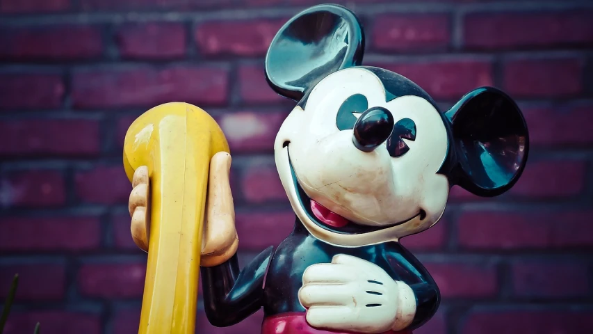 a mickey mouse figurine holding a yellow telephone, by Walt Disney, pexels, art nouveau, banana, the straw is in his mouth, photorealism. trending on flickr, theme park