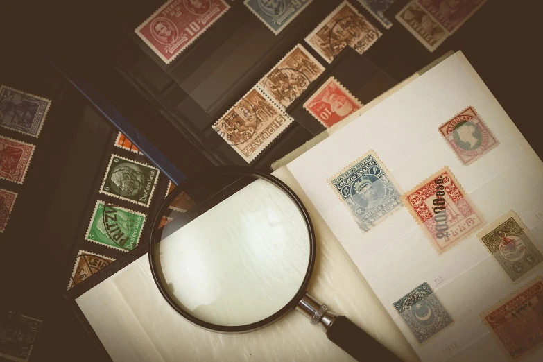 a magnifying glass sitting on top of a piece of paper, a stock photo, by Eugeniusz Zak, shutterstock, art nouveau, on a poststamp, vintage color photo, close macro photo. studio photo, various point of view