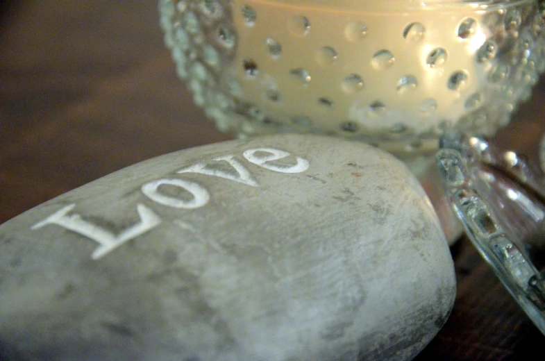 a candle and some rocks on a table, by Magdalene Bärens, flickr, concrete art, love theme, font, close - up on detailed, brushed