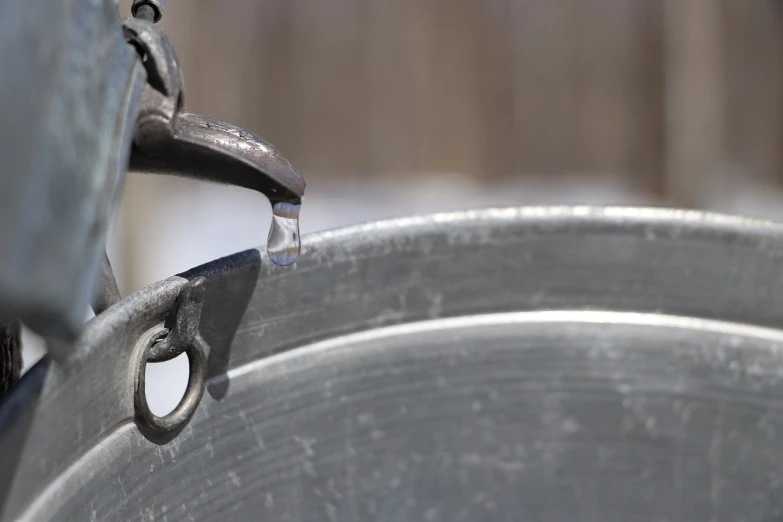 a close up of a metal pan with water coming out of it, by Jan Rustem, process art, saws, gray, icy, banner