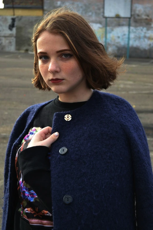 a close up of a person wearing a coat, inspired by Louisa Matthíasdóttir, cg society contest winner, dark blue cape, vintage inspired, britt marling style, wearing several pendants
