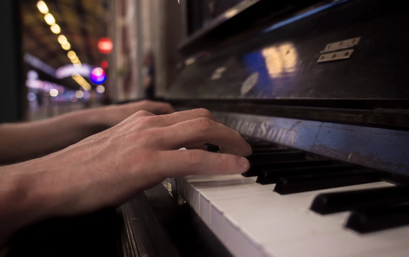 a close up of a person playing a piano, a picture, by Matt Cavotta, city scene, postprocessed, background bar, hands