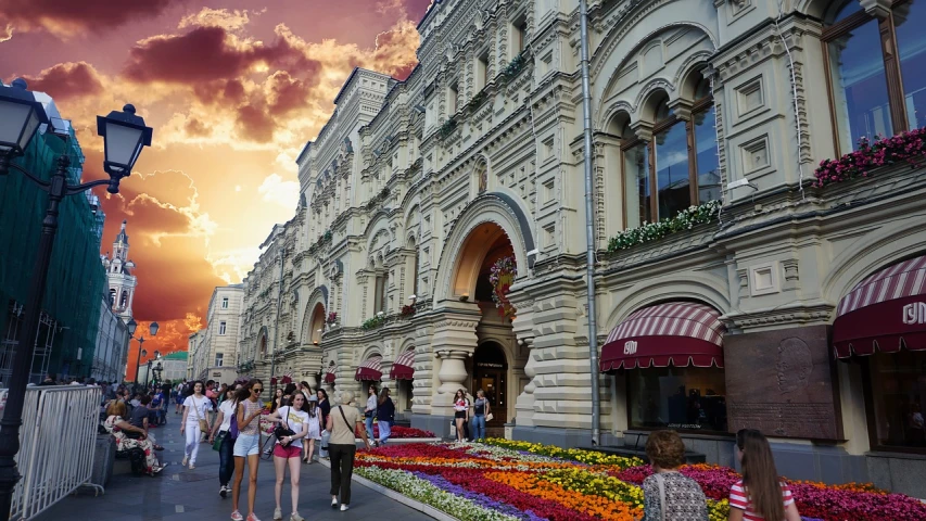 a group of people walking down a street next to tall buildings, a picture, by Fyodor Rokotov, art nouveau, floral sunset, moscow kremlin, july 2 0 1 1, covered with flowers