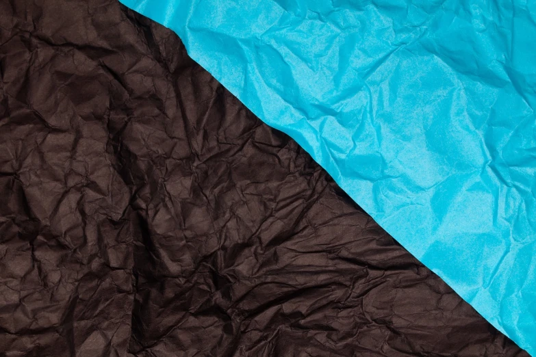 a black and blue blanket sitting on top of a bed, a stock photo, minimalism, paper crumpled texture, brown and cyan blue color scheme, two - tone, abstract claymation