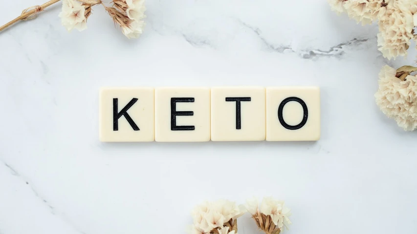 the word keto spelled in scrabbles on a marble surface, a picture, by Matt Cavotta, shutterstock, art deco, mukbang, 🦩🪐🐞👩🏻🦳, bottom - view, jello