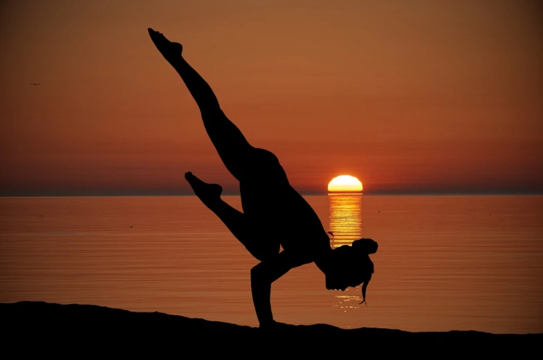 a person doing a handstand on a beach at sunset, a picture, by Eva Gonzalès, arabesque, doing martial arts, olga buzova, breakdancing, lizard pose