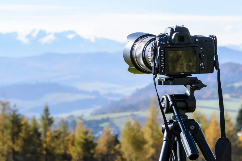 a close up of a camera on a tripod, a picture, by Matthias Weischer, shutterstock, mountains on background, 4 k cinematic panoramic view, uhd photography, set photo