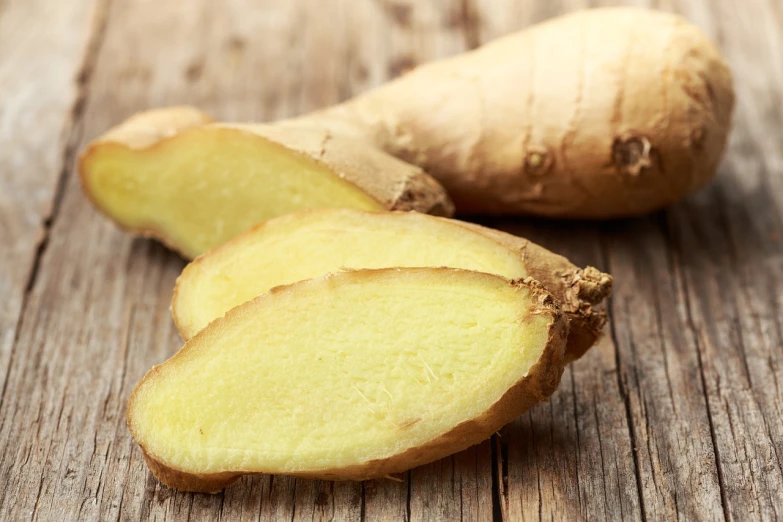 a close up of a sliced ginger on a wooden table, a portrait, shutterstock, high quality product image”