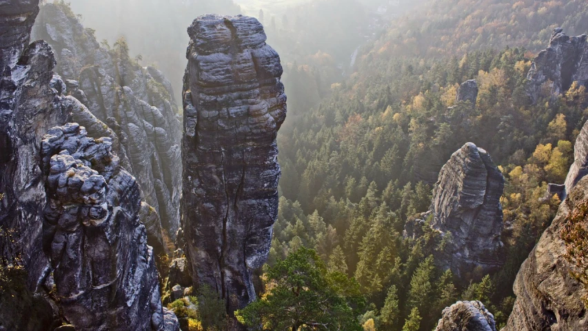 a large rock formation in the middle of a forest, by Emanuel Büchel, pexels contest winner, art nouveau, towering high up over your view, very long spires, closeup - view, lotz karoly