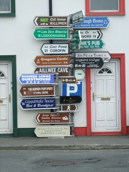 a bunch of street signs on a pole in front of a building, by Edward Corbett, flickr, ireland, cottage town, many doorways, poker