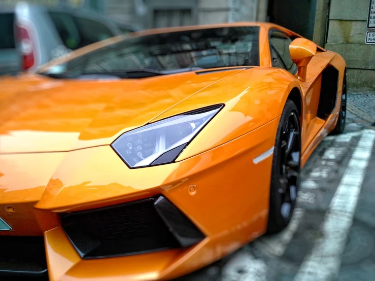 an orange sports car parked on the side of the road, a picture, by Alexander Robertson, pexels contest winner, photorealism, lamborghini, macro up view metallic, sharp lighting. bright color, view from the streets