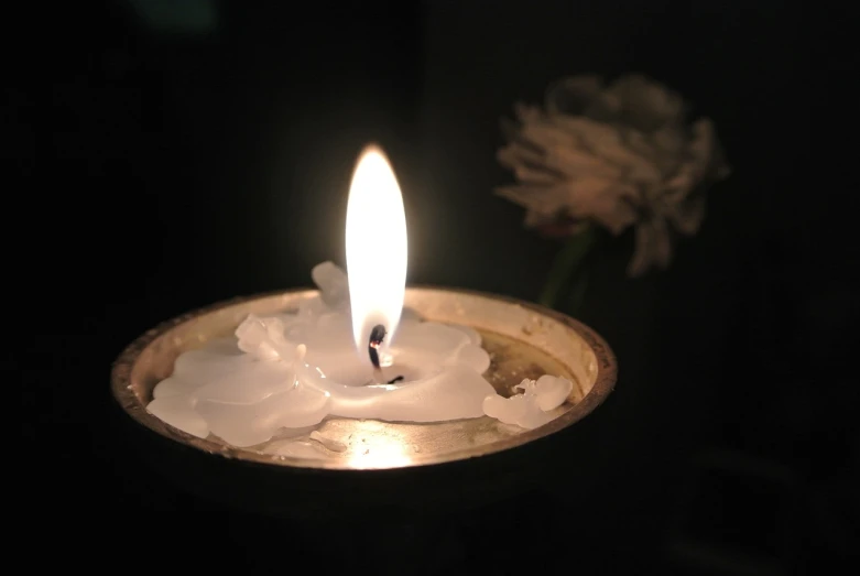 a close up of a candle with a flower in the background, flickr, vanitas, burning water, white wax, photo taken at night, high res photo