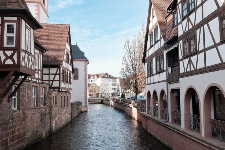 a river running through a town next to tall buildings, a photo, by Tobias Stimmer, renaissance, timbered house with bricks, slightly sunny weather, in town, rossbach