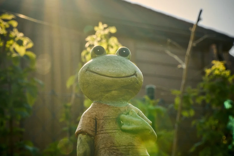 a close up of a statue of a frog, a picture, unsplash, sun behind him, in the garden, claymation character, with a happy expression