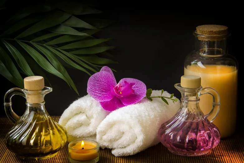 a bunch of towels sitting on top of a table, a portrait, by Rhea Carmi, shutterstock, renaissance, orchids, glowing oil, with a black dark background, high detail product photo