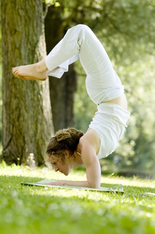 a woman doing a handstand in a park, by Robert Medley, shutterstock, side profile view, ap photo, sukhasana, 872637744