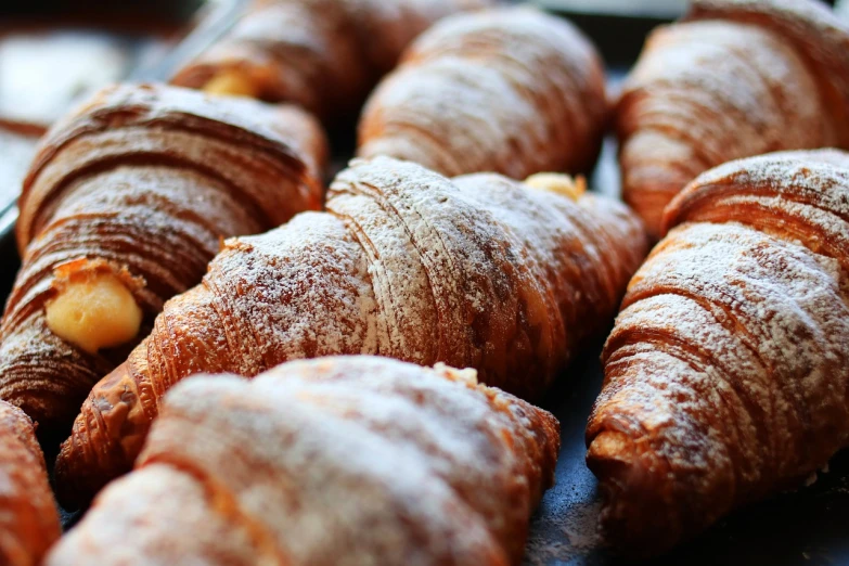 a tray filled with croissants covered in powdered sugar, a portrait, by Antonio Saura, pexels, renaissance, in a row, tocchini, early in the morning, 4 0 0 mm