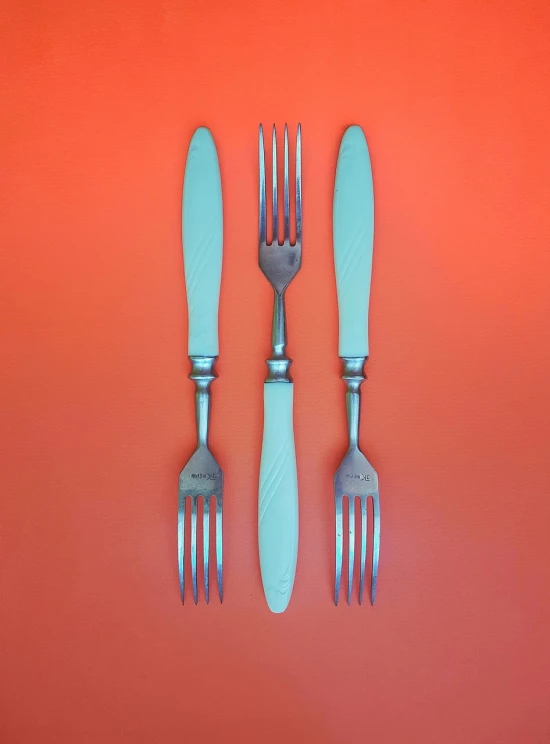 a couple of forks sitting on top of a table, a pastel, inspired by Gustave Boulanger, unsplash, dau-al-set, 3 - piece, salmon, turquoise, stainless steal