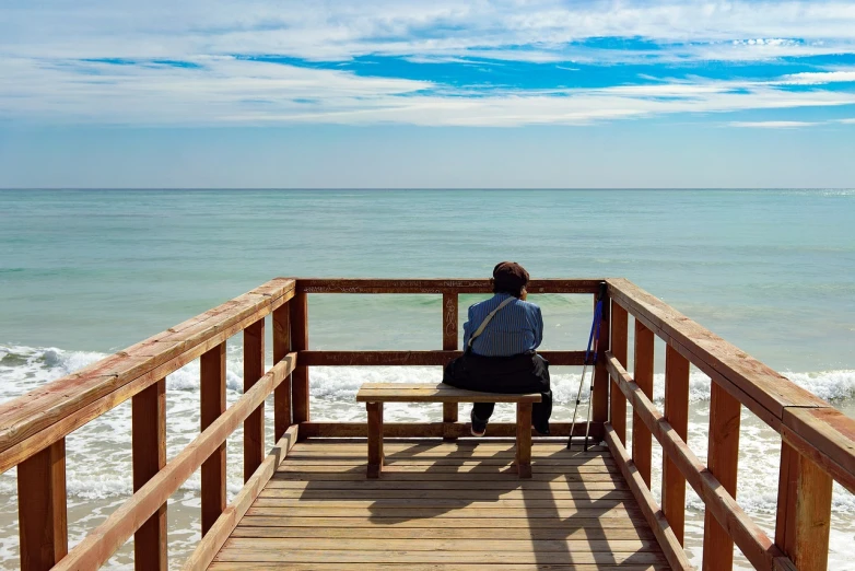 a person sitting on a bench looking out at the ocean, a picture, by senior artist, shutterstock, fine art, florida, stock photo, people angling at the edge, a lonely woman