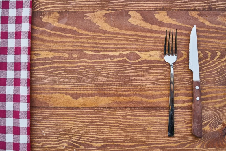 a knife, fork and napkin on a wooden table, a stock photo, shutterstock, folk art, bar background, redwood background, seen from straight above, fork fork fork