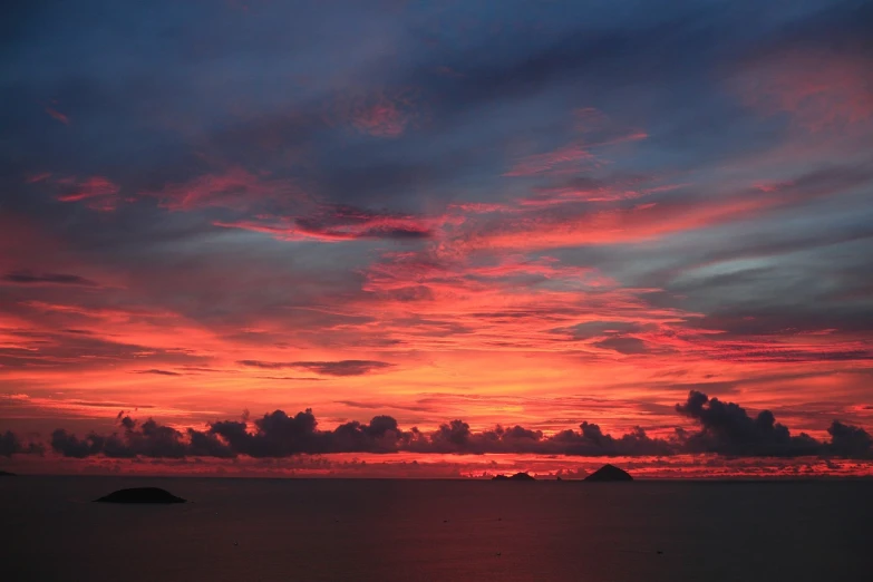 a large body of water with a sunset in the background, by Charlotte Harding, flickr, bright colors with red hues, tropical atmosphere, koyaanisqatsi, an amazing photo