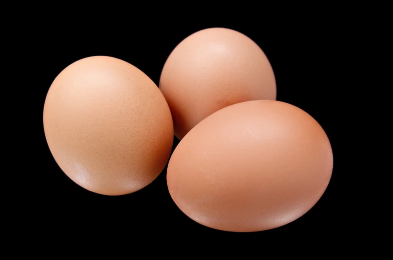 three eggs sitting next to each other on a black surface, highly detailed product photo, istockphoto, brown, angled