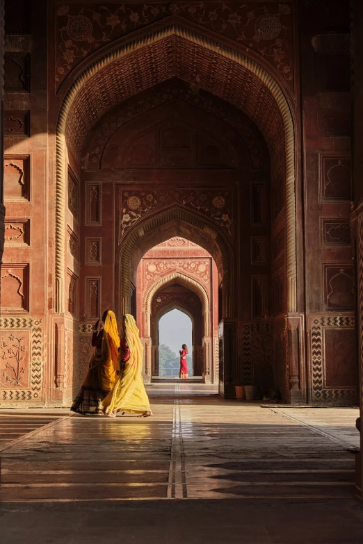 a couple of women standing next to each other in a building, a picture, inspired by Steve McCurry, unsplash contest winner, renaissance, taj mahal, yellow and red color scheme, gate, intricate robes