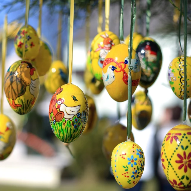 a bunch of painted eggs hanging from a tree, by Erwin Bowien, shutterstock, folk art, yellow, museum quality photo, in a sunny day, close-up photo