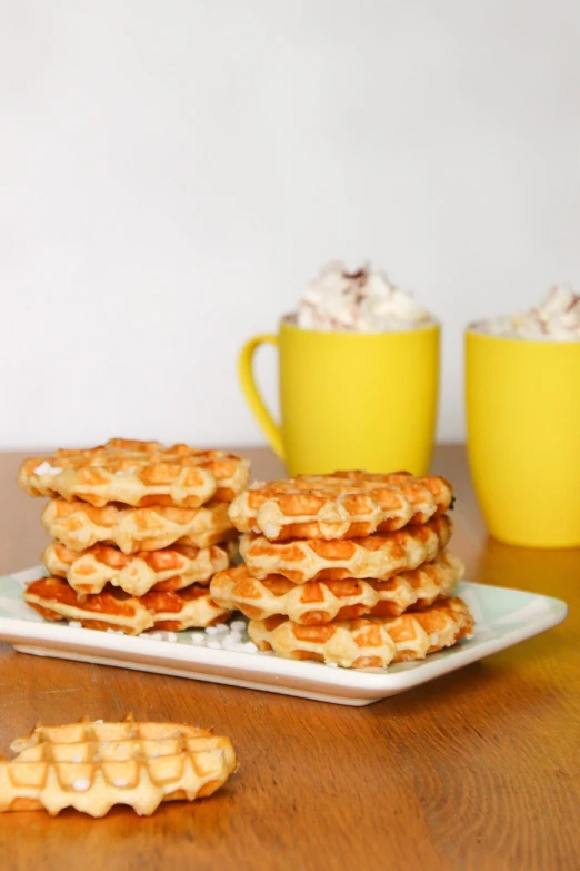 a plate of waffles sitting on top of a wooden table, inspired by Ödön Márffy, dau-al-set, stacked, daisy, cookies, belgium