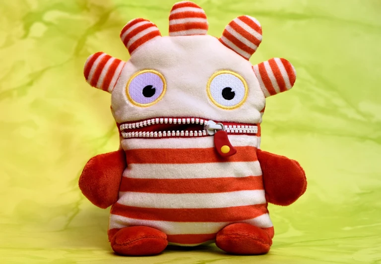 a close up of a stuffed animal on a green background, a photo, cute monster character design, red and white stripes, highly detailed product photo, zippers
