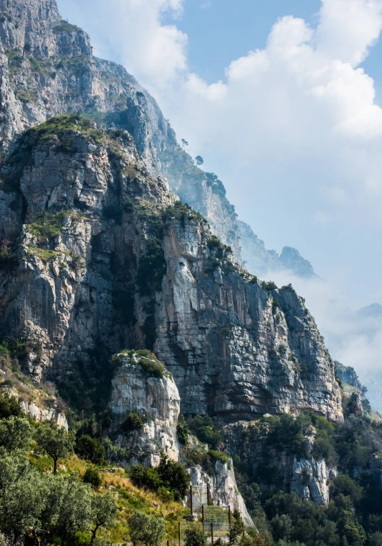 a herd of cattle standing on top of a lush green hillside, a detailed matte painting, by Etienne Delessert, pexels, figuration libre, capri coast, mountains in fog background, extremely detailed rocky crag, photo taken from a boat
