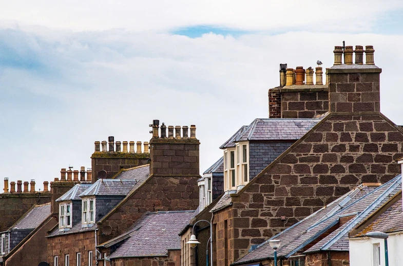 a clock that is on the side of a building, a tilt shift photo, by John Murdoch, shutterstock, chimneys on buildings, orkney islands, in a row, residential area